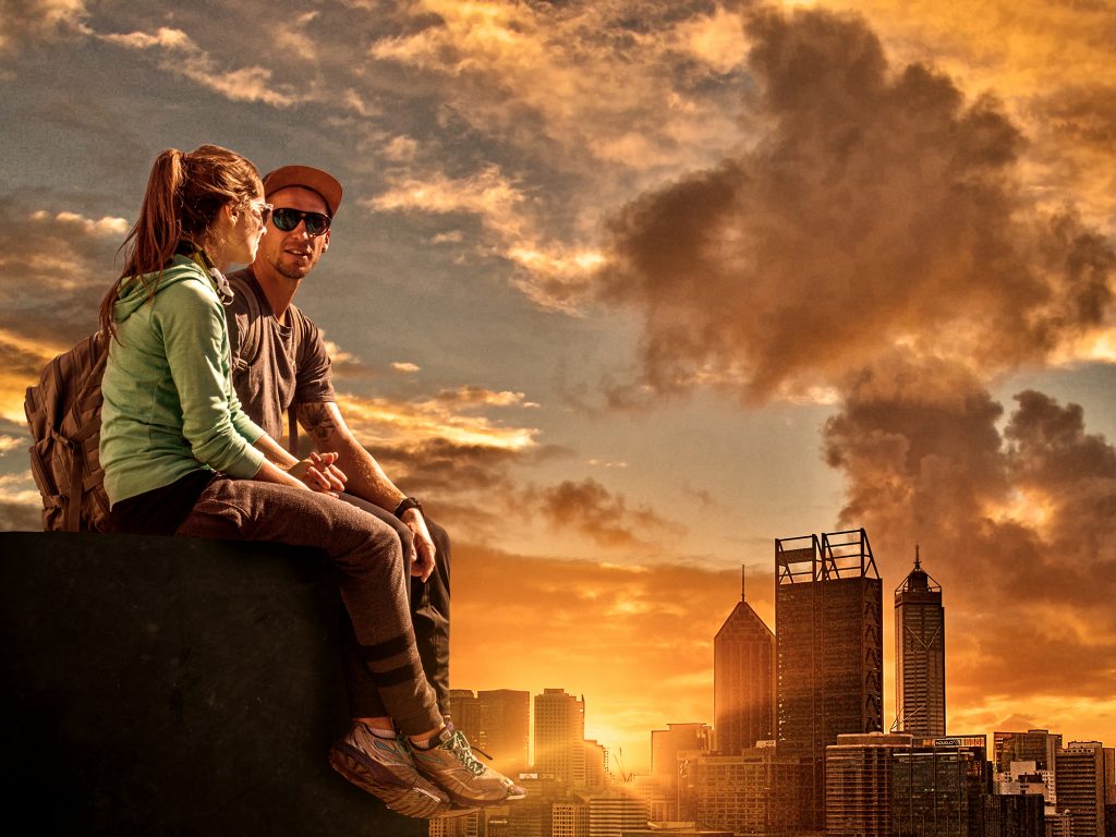 romantic couple sitting atop skyscraper at sunset